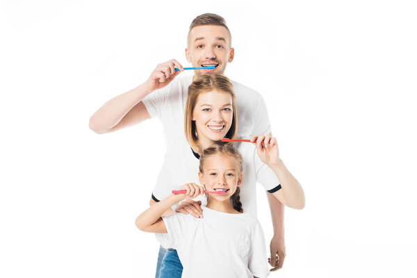 portrait of smiling family in similar clothing with toothbrushes isolated on white