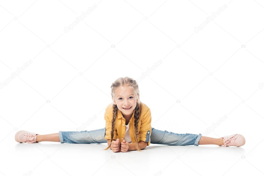 smiling little child stretching, doing split and looking at camera isolated on white