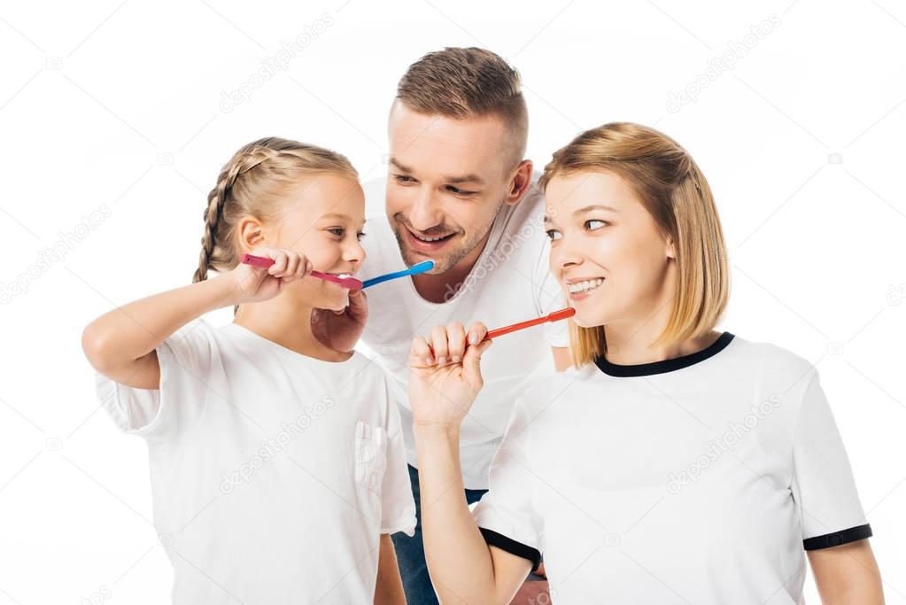 portrait of family in similar clothing brushing teeth isolated on white