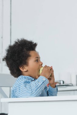 çok güzel Afro-Amerikan çocuk evde elma ısırma yan görünüm