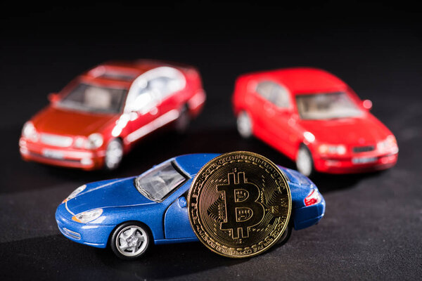 close-up view of bitcoin and car models on black