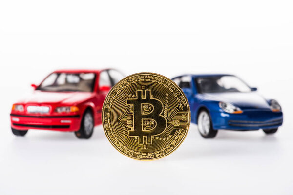 close-up view of bitcoin and car models on white 