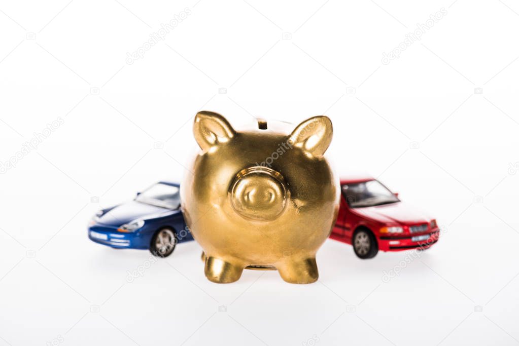 close-up view of golden piggy bank and small cars isolated on white