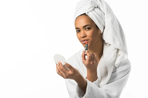 有吸引力的非洲裔美国妇女在浴袍和毛巾用镜子涂抹口红 白色隔离 — 图库照片