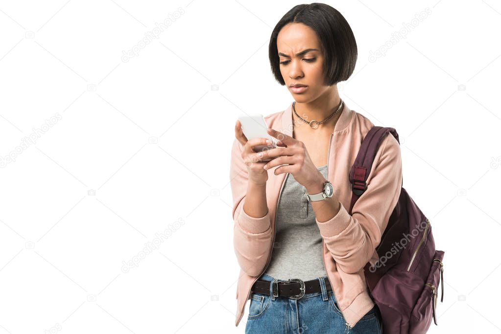 confused african american student with backpack using smartphone,  isolated on white