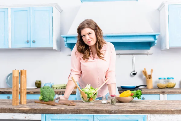 自宅のキッチンで新鮮なサラダとテーブルで立っている太りすぎの女性の肖像画 — ストック写真