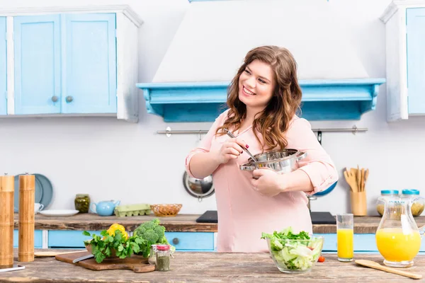 自宅の台所で鍋に立って笑顔の太りすぎの女性の肖像画 — ストック写真