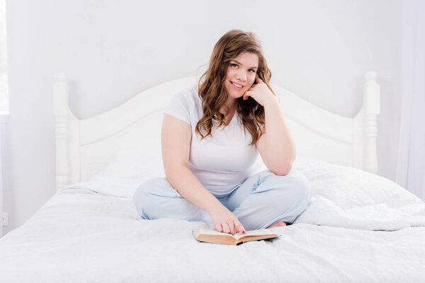 young woman in pajama with book on bed at home
