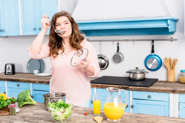 Portrait of young overweight woman cooking soup in kitchen at home — Stock Image Portrait Young Overweight Woman Cooking Soup Kitchen Home Royalty Free Stock Images