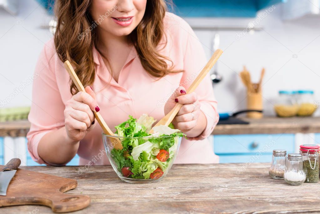 partial view of overweight woman cooking fresh salad for dinner in kitchen at home