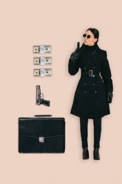 güneş gözlüğü evrak çantası, tabanca ve para çekme, pembe arka plan izole kadın katilin Üstten Görünüm