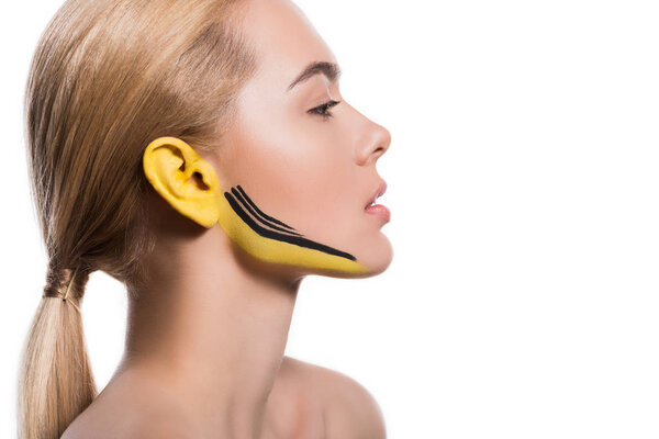 side view of attractive woman with yellow and black paints on ear and face isolated on white