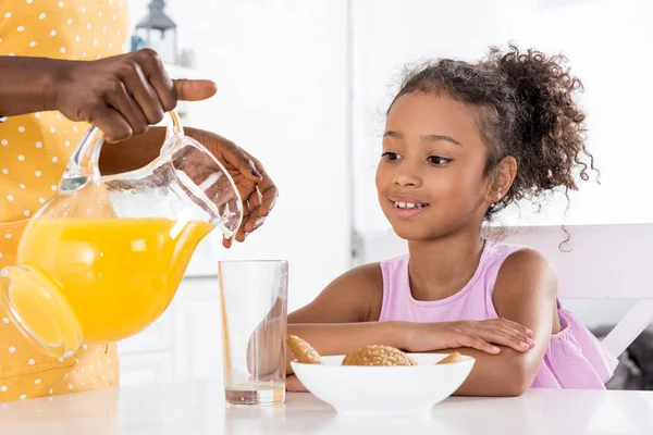 Afro Americana Mãe Derramando Suco Laranja Para Filha Cozinha — Fotografia de Stock