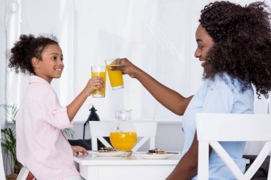 mutlu Afrika kökenli Amerikalı anne ve kızı tungur bardak portakal suyu ile 