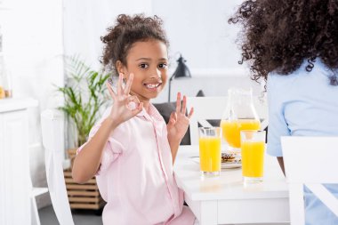 Afrika kökenli Amerikalı anne ve kızı gösteren işaretler yemek salonunda kahvaltı sırasında ok