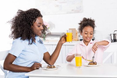 Afrika kökenli Amerikalı anne ve kızı kahvaltı krep ve portakal suyu ile mutfak
