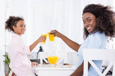 Afrika kökenli Amerikalı anne ve kızı tungur bardak portakal suyu ile gülümseyen 