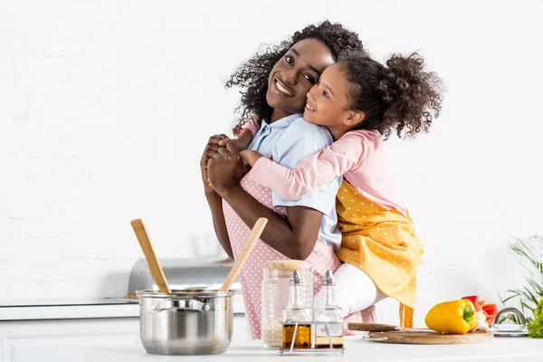 非洲裔美国人母亲在厨房围裙上扛女儿 — 图库照片