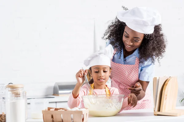 キッチンに生地を混ぜて料理シェフ帽子でアフリカ系アメリカ人の母と娘 — ストック写真