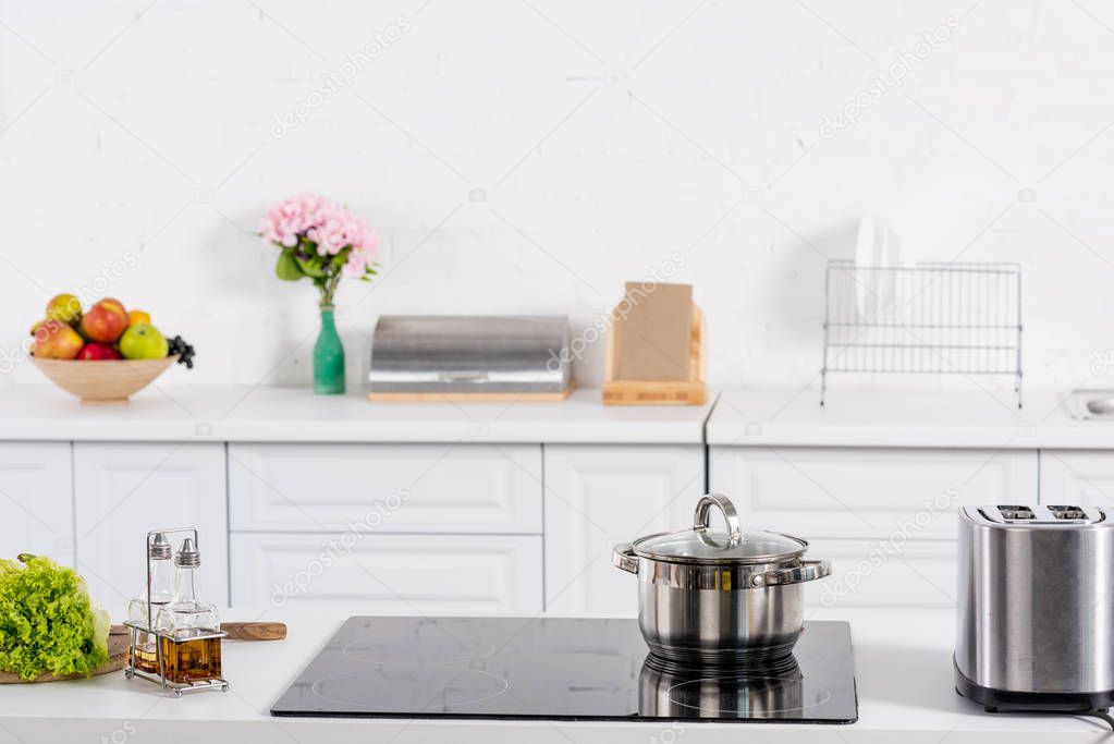 toaster and electric stove with saucepan on kitchen