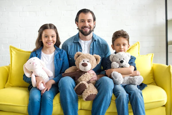 愉快的父亲与二个可爱的孩子拿着玩具和微笑在照相机在家 — 图库照片