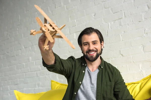 Glücklicher Junger Mann Spielt Mit Holzspielzeugflugzeug Und Lächelt Die Kamera — Stockfoto