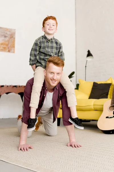 happy father and son smiling at camera while having fun together at home