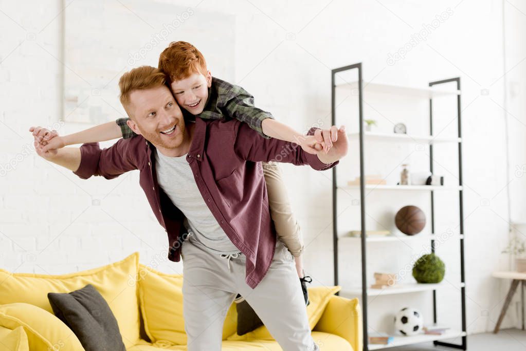 cheerful redhead father and son having fun together at home