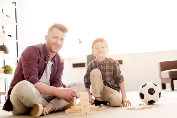 快乐的父亲和儿子在相机微笑 而玩木块和足球在家里 — 图库照片