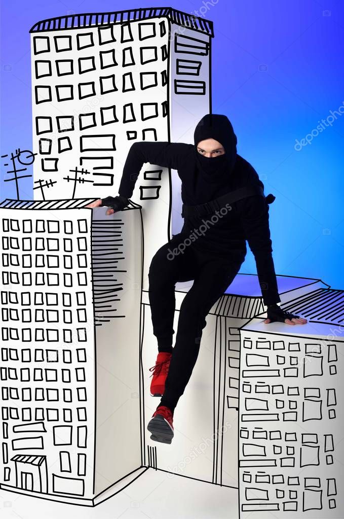 ninja in black clothing with katana behind getting across on drawing buildings on blue