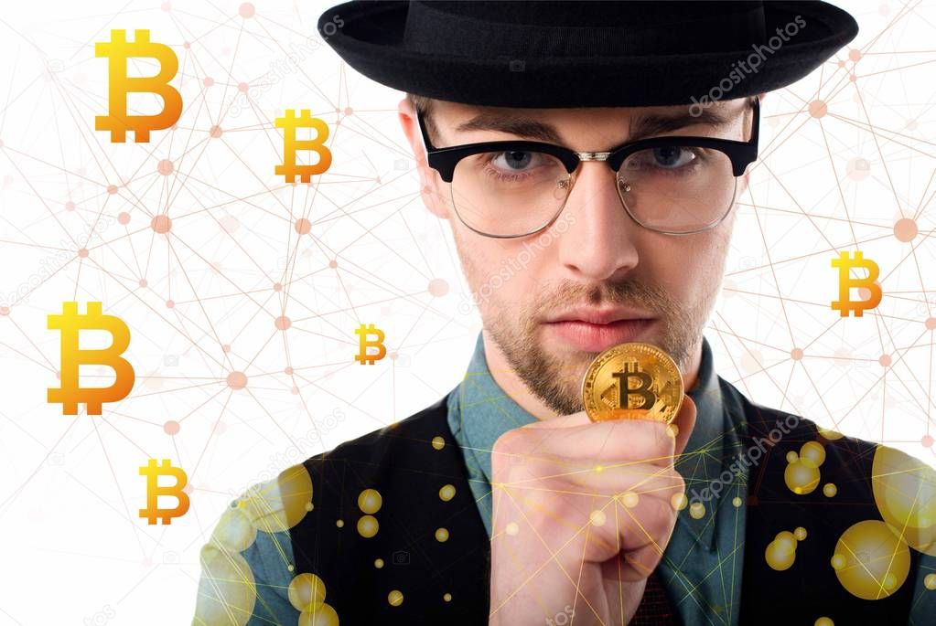 Portrait of man in eyeglasses and hat holding golden bitcoin on white