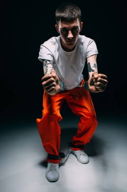 Turuncu kelepçeleri koyu arka plan üzerinde gösterilen tek tip üzgün adam