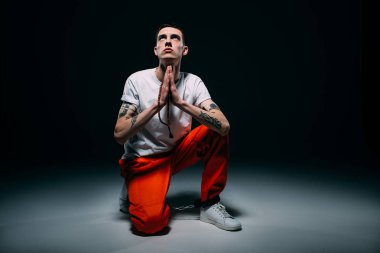 Adam turuncu pantolon ve tespih tutan ve koyu arka plan üzerinde dua kelepçeleri