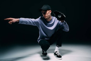 Koyu arka plan üzerinde basketbol oynarken eldiven giyiyor şapkalı adam