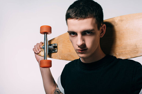 Handsome young man holding longboard on shoulders isolated on white