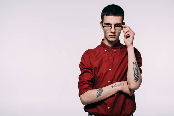 Stylish man with tattoos wearing red shirt and glasses isolated on white