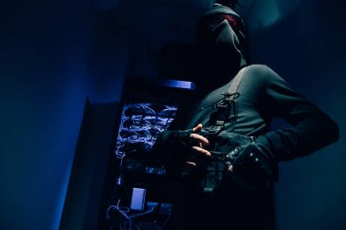 arka plan üzerinde siyah giyim ve gözlük çeşitli kablolar ile hacker düşük açılı görünüş
