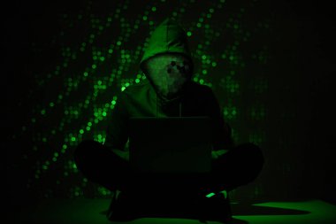 toned picture of hacker silhouette in hoodie using laptop clipart