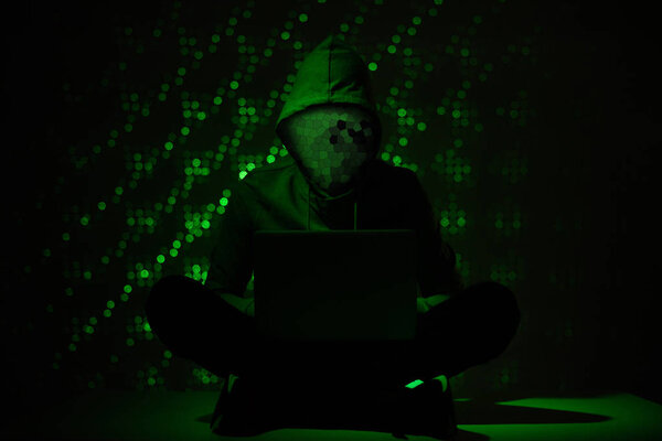 toned picture of hacker silhouette in hoodie using laptop