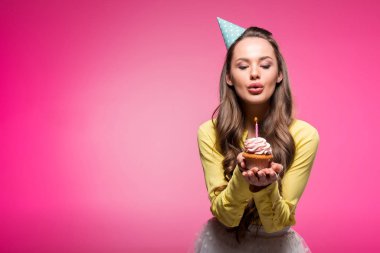 cupcake tutarak ve pink izole mum dışarı üfleme parti şapkası ile çekici kadın