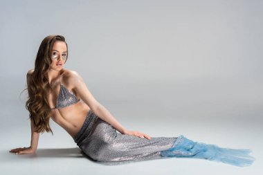 beautiful woman with mermaid tail lying on floor and looking at camera clipart