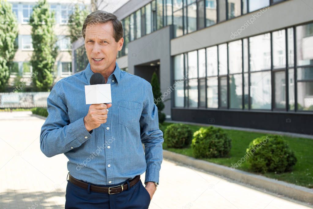 professional mature news reporter talking with microphone   