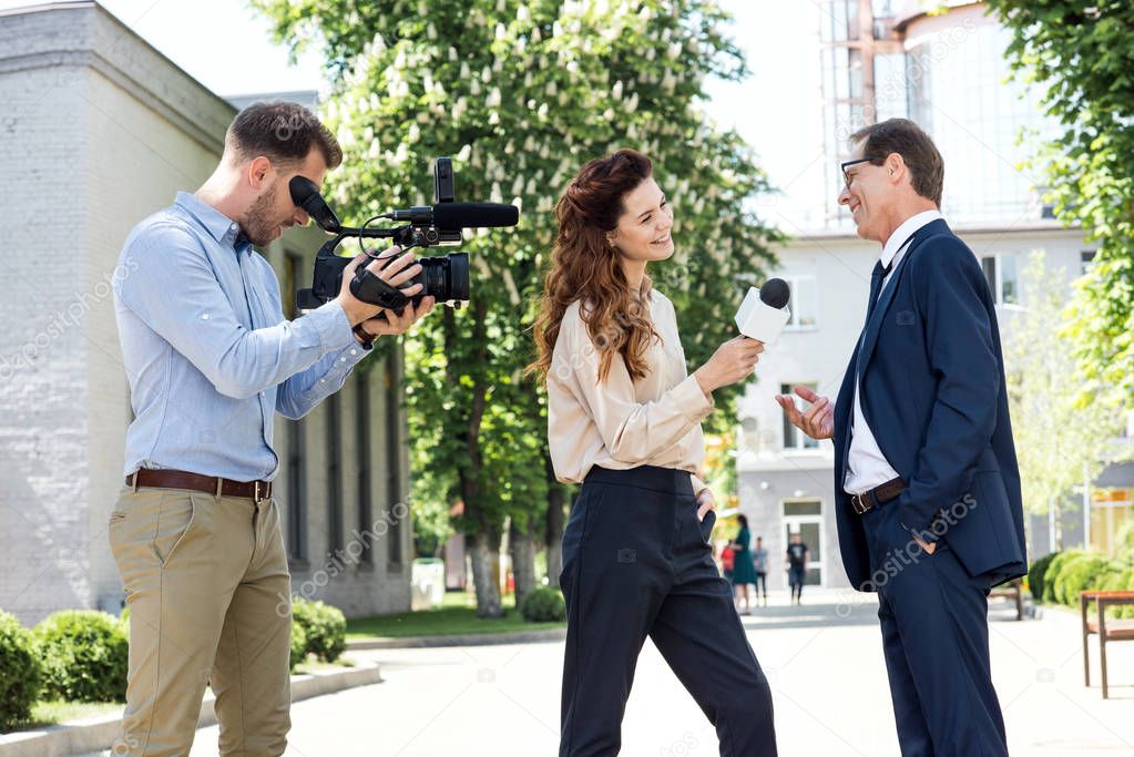 cameraman and female newscaster interviewing businessman  