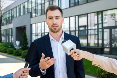 journalists interviewing serious businessman with microphones clipart