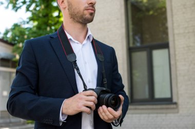 cropped view of photojournalist in formal wear with digital photo camera clipart