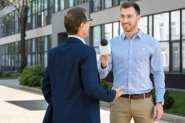 Professioneller Lächelnder Journalist Interviewt Erfolgreiche Geschäftsleute Mit Mikrofon — Stockfoto