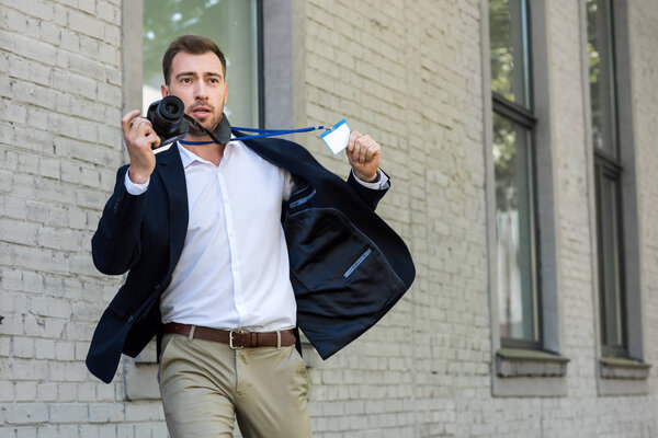 photojournalist running with digital photo camera and press pass