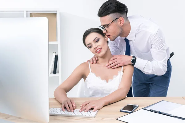 Businessman whispering to beautiful colleague at office — Stock Photo