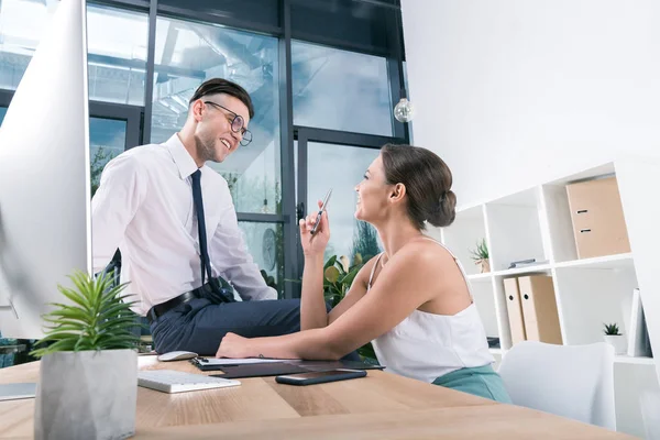 Des gens d'affaires souriants parlant sur le lieu de travail au bureau — Photo de stock