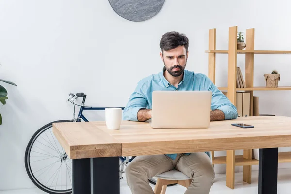 Hombre de negocios con portátil en el lugar de trabajo - foto de stock